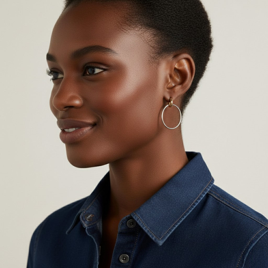 Jonge vrouw met kort haar draagt een gouden creooloorbel van CECELYN in denim blouse.