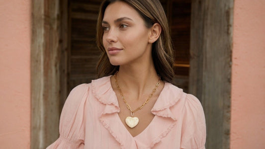 Jonge vrouw in roze blouse met gouden CECELYN-ketting en witte harthanger.