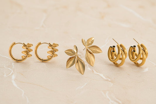 Gouden statementoorbellen van CECELYN: hoops met spiraal, blad-design oorstekers en buisvormige hoops.