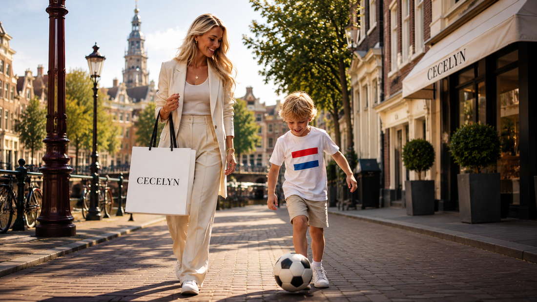 Een moeder met een CECELYN-shoppingtas wandelt langs de grachten, terwijl haar zoontje in een Nederlands vlag-shirt voetbalt tijdens de zomer van het grote voetbaltoernooi.