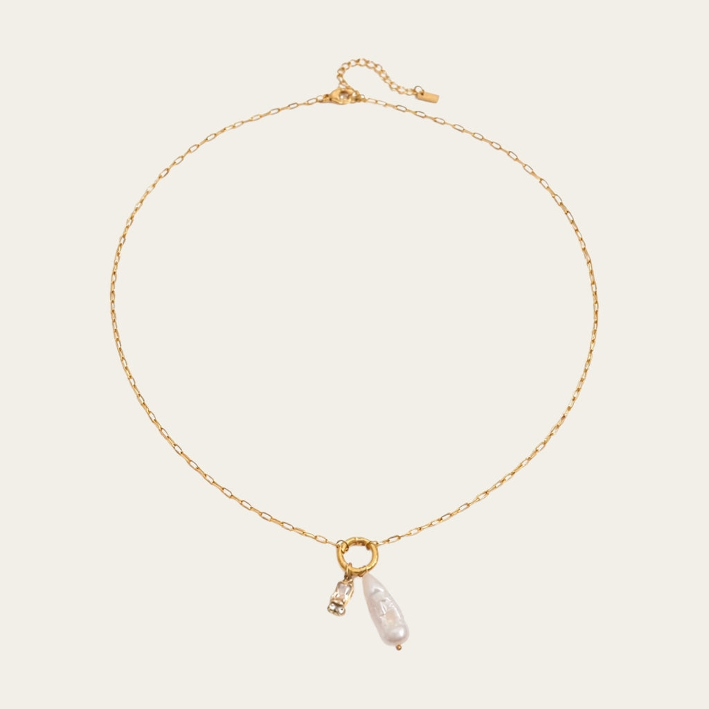 Fashionable gelaagde sieradenstijl met gouden schakelketting, parels en geboortestenen in verschillende kleuren.