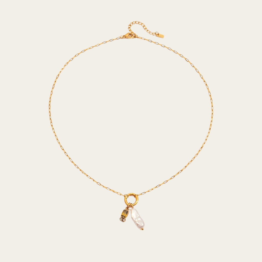 Fashionable gelaagde sieradenstijl met gouden schakelketting, parels en geboortestenen in verschillende kleuren.