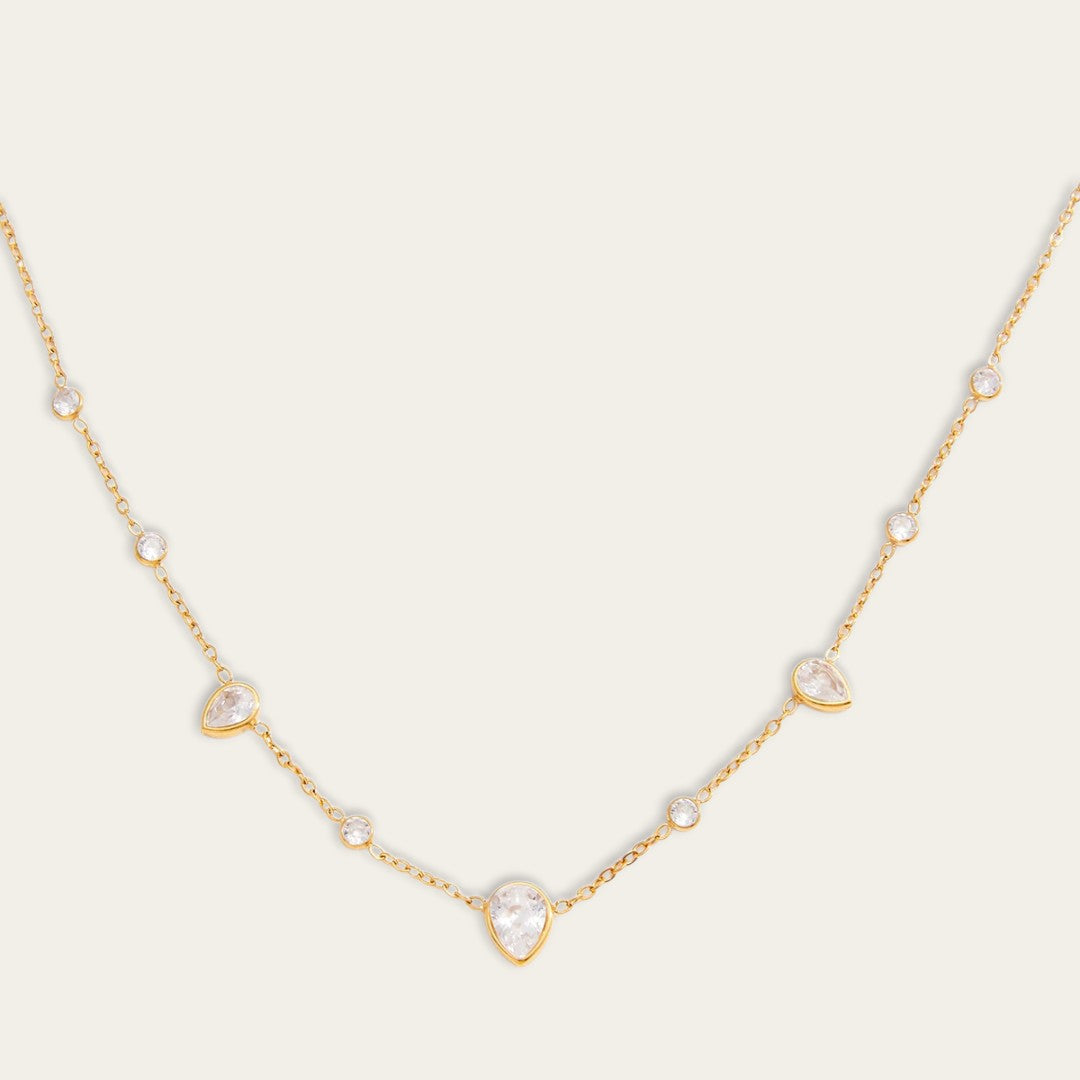 Goudkleurige ketting met fijne schakels, bezet met ronde en peervormige zirkonia steentjes in een subtiele choker stijl.