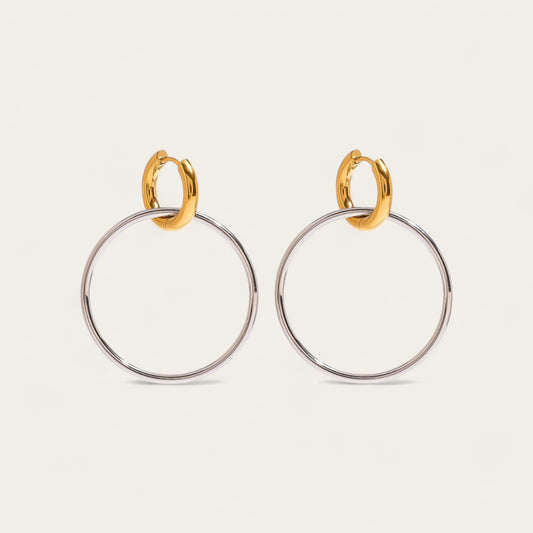 Paar bicolor hoop oorbellen met een kleine gouden huggie en een grote zilveren ring.