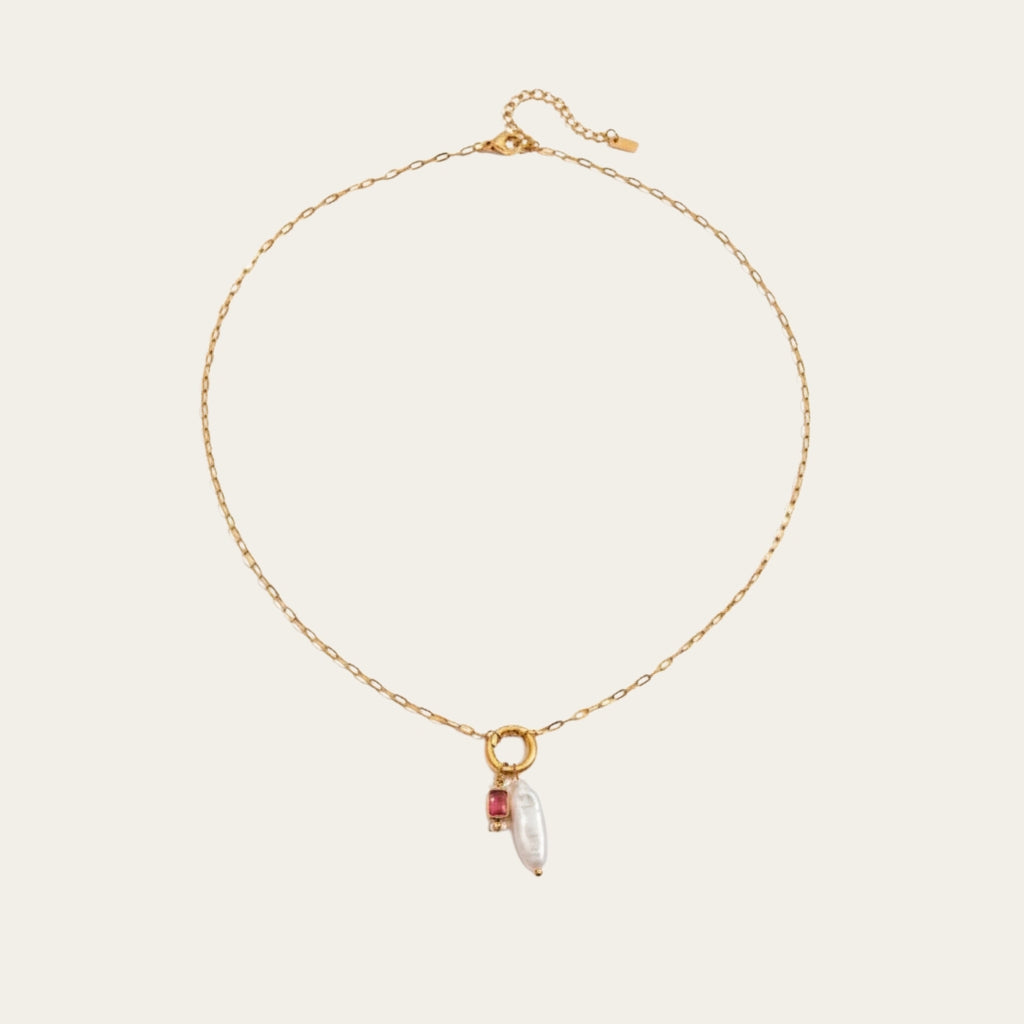 Fashionable gelaagde sieradenstijl met gouden schakelketting, parels en geboortestenen in verschillende kleuren.