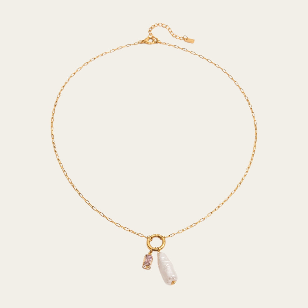Fashionable gelaagde sieradenstijl met gouden schakelketting, parels en geboortestenen in verschillende kleuren.