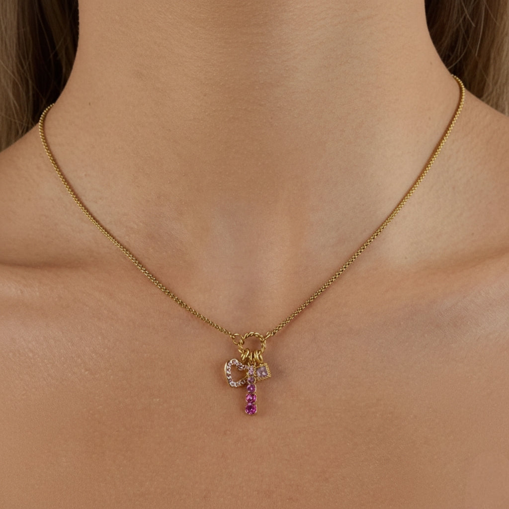 Model draagt een ketting in goud met gradiënt roze kristallen hangers. Een minimalistisch en fashionable sieraad voor dames.