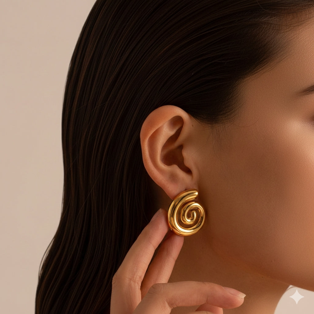 Model draagt minimalistische gouden swirl oorbellen met een organisch gedraaid design en hoogglans finish.