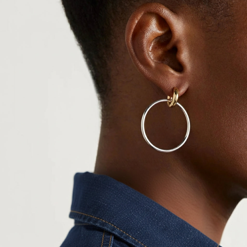 Model draagt minimalistische tweekleurige oorbellen van goud en zilver, duotone hoops voor een moderne en nonchalante look.