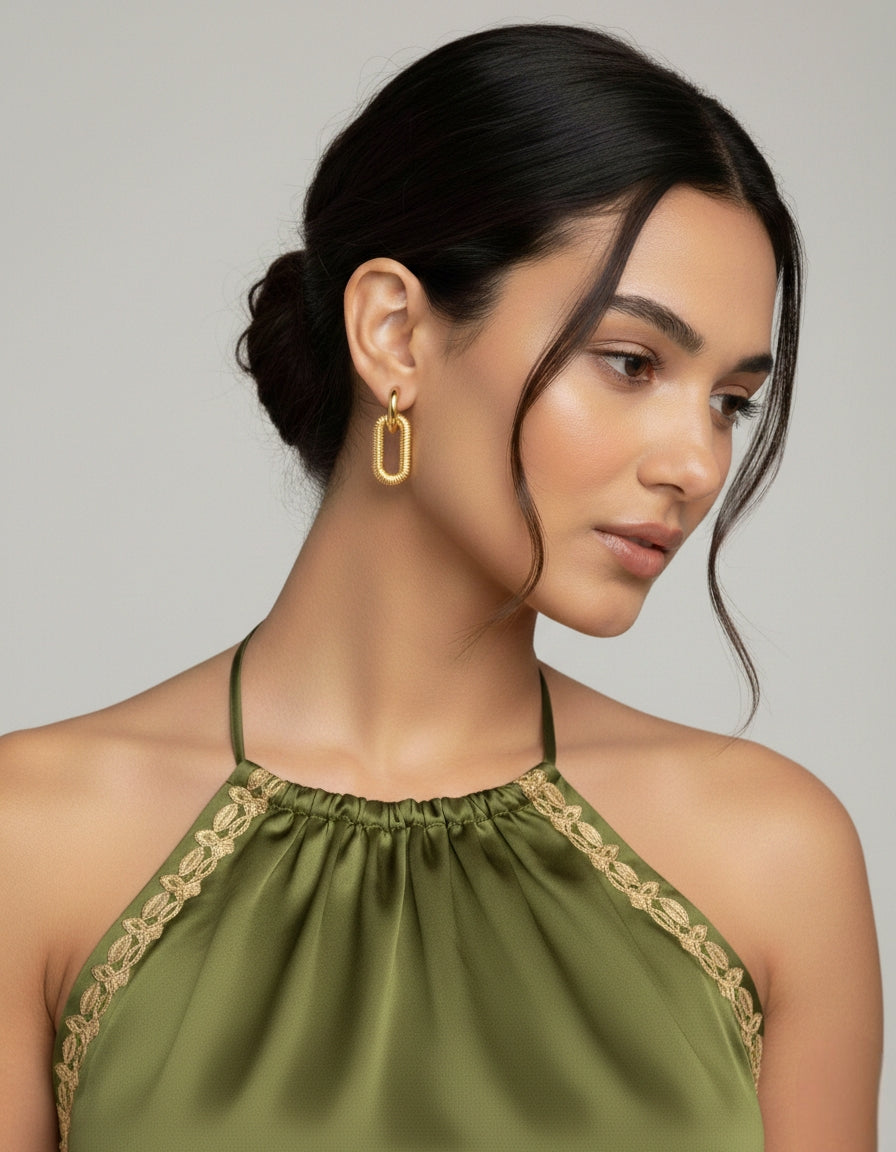 Model draagt chunky gouden schakeloorbellen met textuur en een minimalistisch design voor een nonchalante, fashionable look.