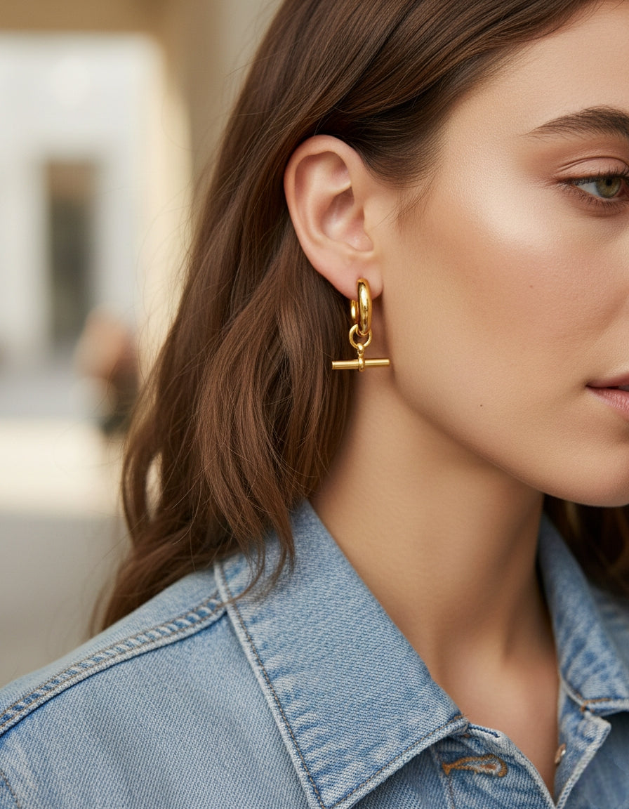 Model draagt gouden T-bar oorringen van roestvrij staal – minimalistische bedel oorbellen voor dames