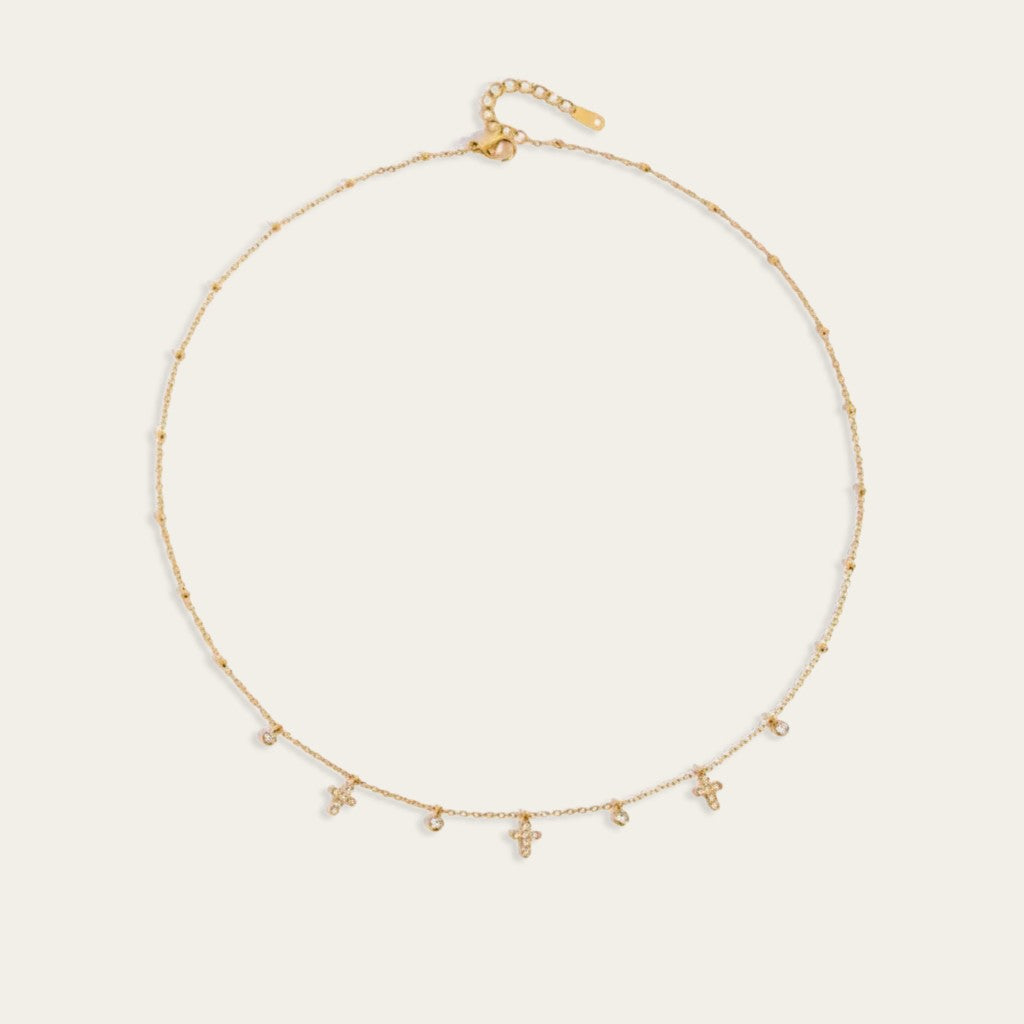 Gouden choker ketting met kleine kruisjes en ronde zirkonia steentjes.