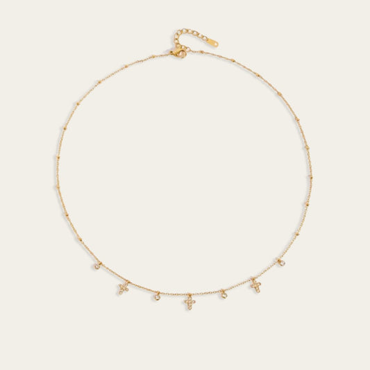 Gouden choker ketting met kleine kruisjes en ronde zirkonia steentjes.