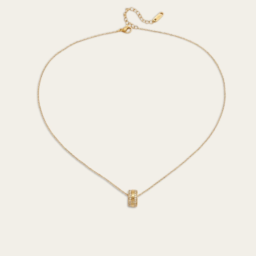Gouden damesketting van Cecelyn met een kleine cilindervormige bedel en fijne schakels op een lichte achtergrond.