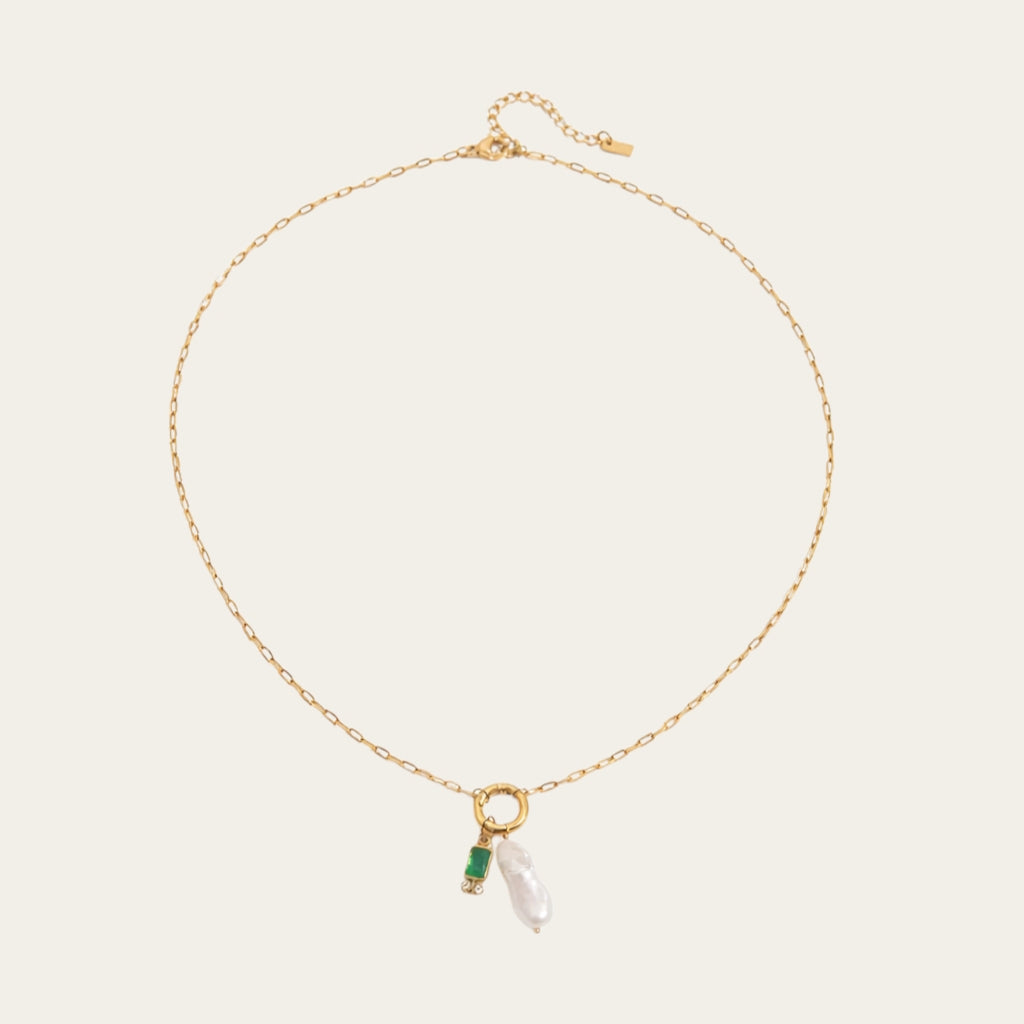 Fashionable gelaagde sieradenstijl met gouden schakelketting, parels en geboortestenen in verschillende kleuren.
