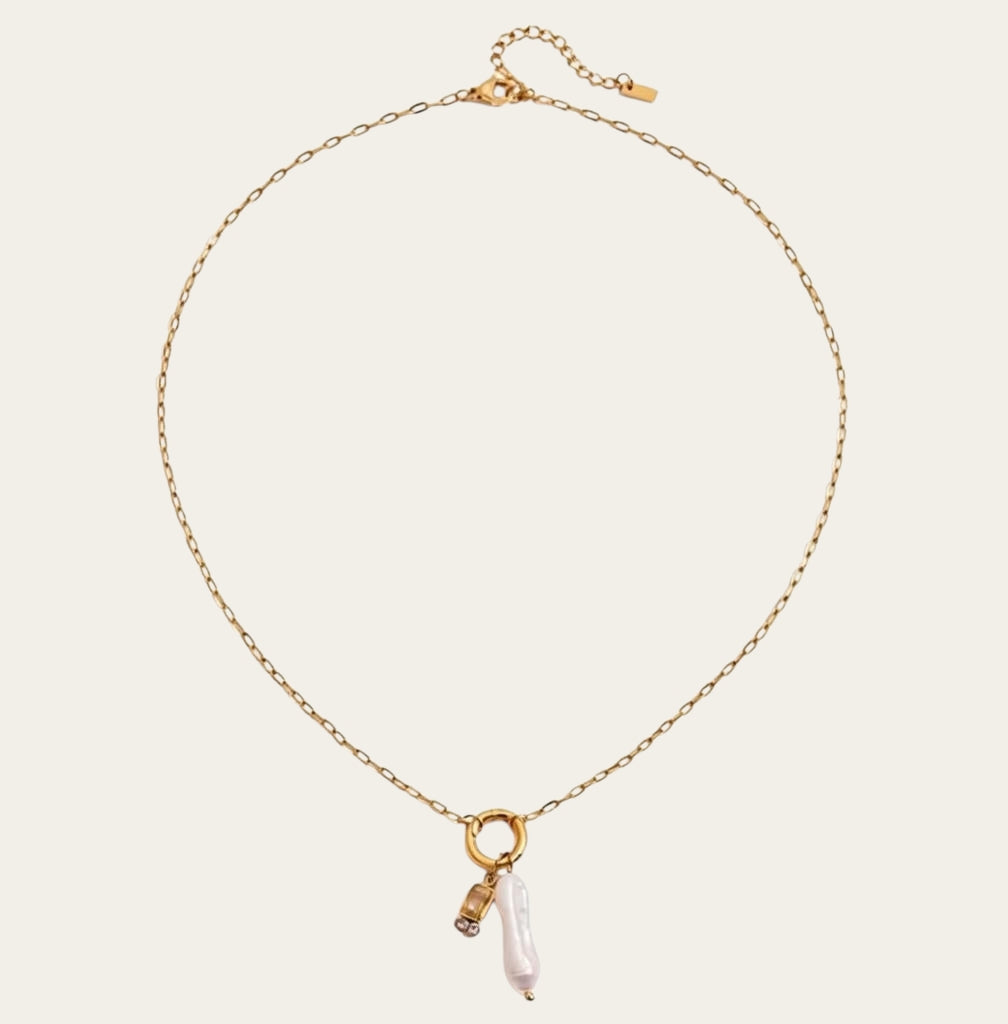 Fashionable gelaagde sieradenstijl met gouden schakelketting, parels en geboortestenen in verschillende kleuren.