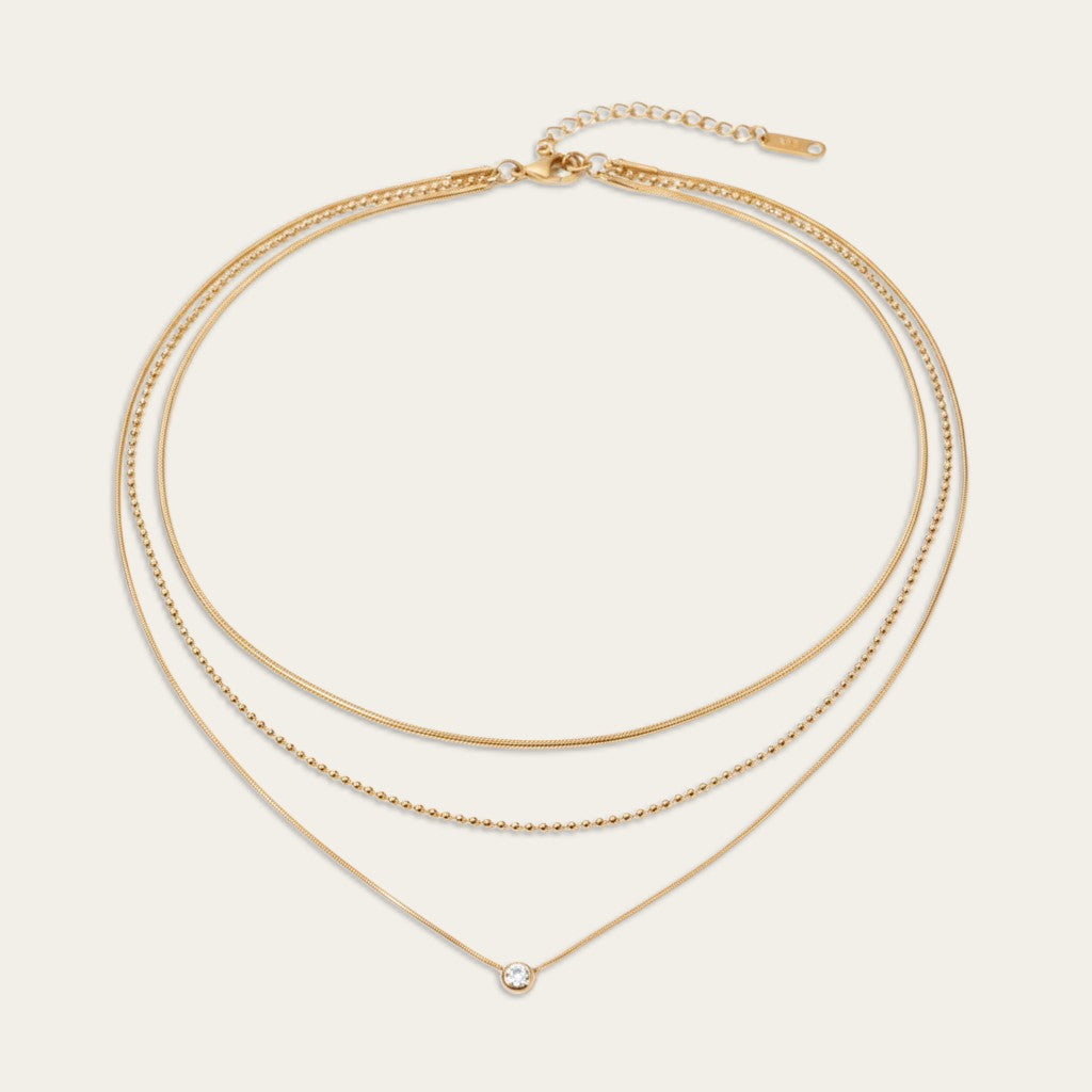 Drielaagse gouden damesketting met snake chain, bolletjesketting en een ronde solitair hanger.