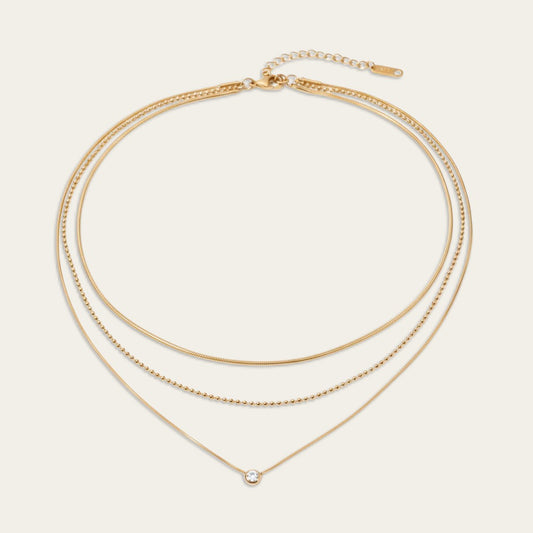 Drielaagse gouden damesketting met snake chain, bolletjesketting en een ronde solitair hanger.