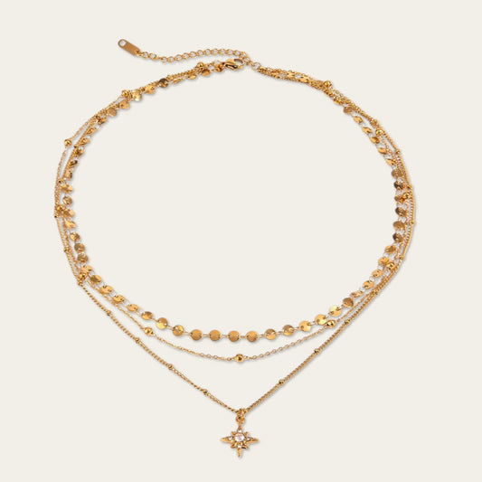 Gelaagde gouden ketting met drie lagen, kleine muntjes en een fonkelende ster-hanger.